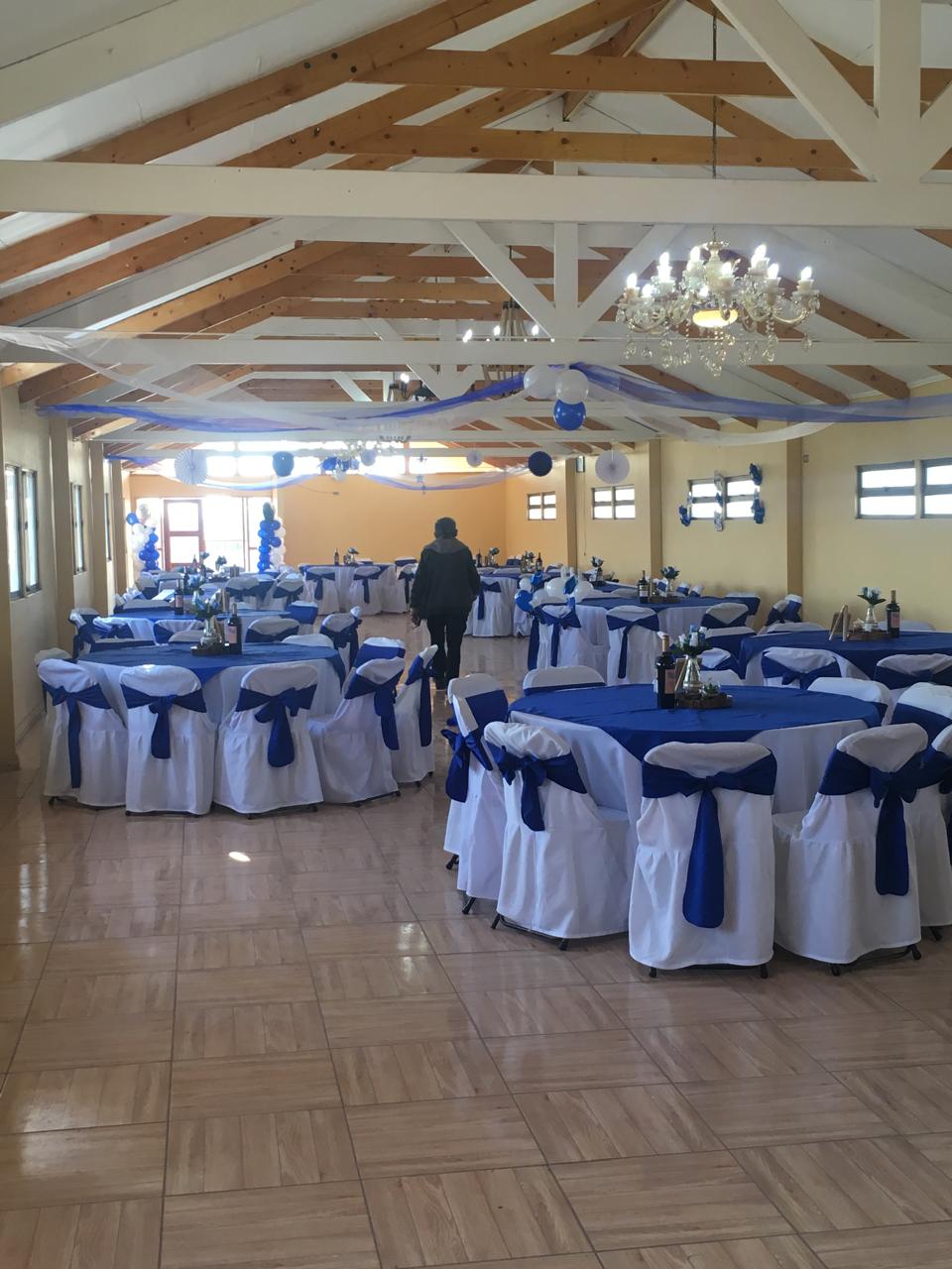 Salón de eventos decorado en blanco y azul, con lámparas de cristal