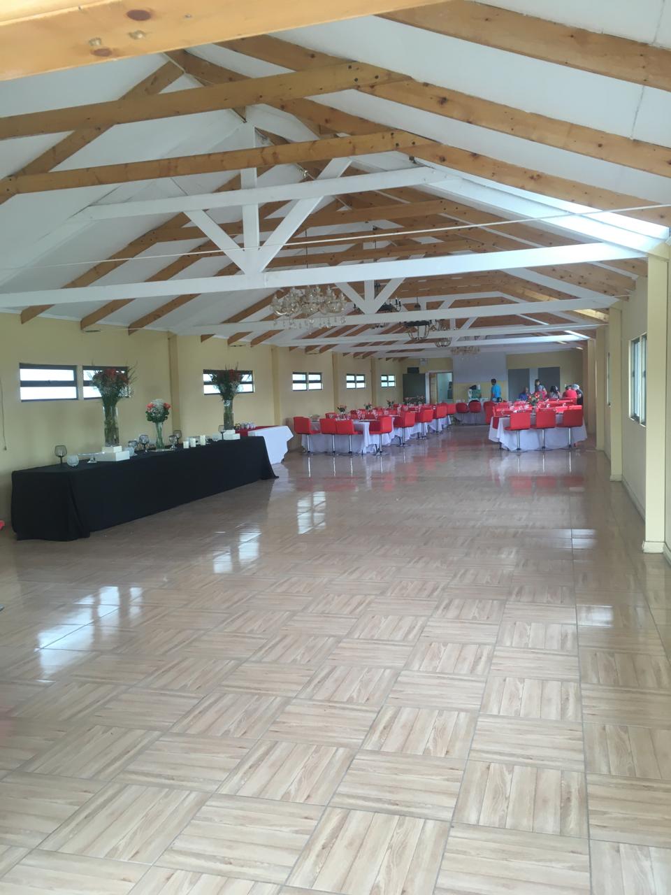 Salón de eventos con pista de baile y sillas rojas